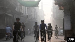 Cyclists ride along a street as they participate in an awareness campaign against smog and pollution in Lahore on November 3, 2024.