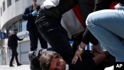 In this May 1, 2020, file photo, Turkish police officers arrest a demonstrator wearing a face mask for protection against the coronavirus, during May Day protests near Taksim Square, in Istanbul.