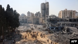 People walk on rubble at the damaged building complex of the U.N. Relief and Works Agency in Gaza City on July 12, 2024, following the withdrawal of Israeli troops from the area. Israel wants to dismantle the UNRWA, but U.N. leader Antonio Guterres says there are no alternatives.