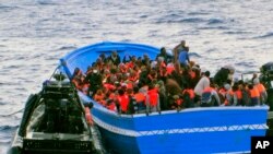 In this photo released by the Italian Navy on May 22, 2014, a fishing boat filled with migrants receives aid from an Italian Navy motor boat. 