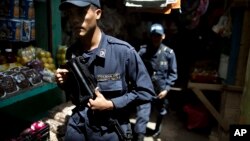 FILE - Honduras National Police officers patrol in El Mayoreo market in Tegucigalpa, Honduras, June 1, 2013. 