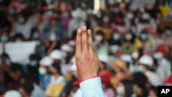 A protester flash the three-fingered salute during an anti-coup protest outside the Hledan Centre in Yangon, Myanmar, Sunday, Feb. 21, 2021. Police in Myanmar shot dead at least a few anti-coup protesters and injured several others on Saturday as security forces increased pressur