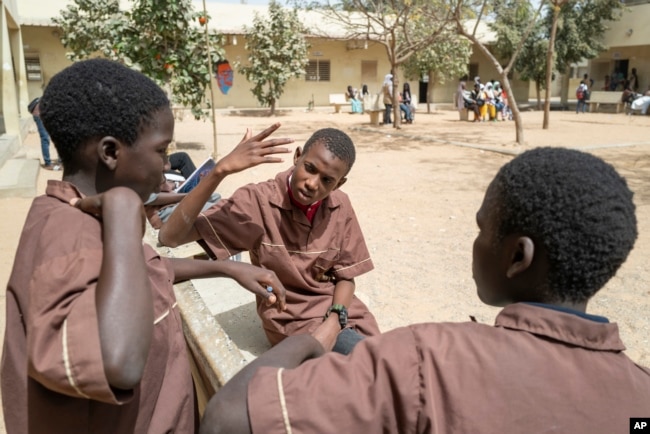 Mouhamed Sall, who is deaf, communicates by sign with his classmates at the Guinaw Rail Sud public high school in Pikine, Senegal, Monday, March 18, 2024. (AP Photo/Sylvain Cherkaoui)