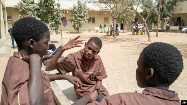 Mouhamed Sall, who is deaf, communicates by sign with his classmates at the Guinaw Rail Sud public high school in Pikine, Senegal, Monday, March 18, 2024. (AP Photo/Sylvain Cherkaoui)