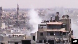 Hình chụp từ video nghiệp dư cho thấy khói bốc lên từ các tòa nhà ở Homs sau các vụ pháo kích 