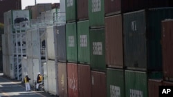 Pekerja pelabuhan mengobrol di samping tumpukan kargo di terminal peti kemas di Tokyo, 19 Februari 2015. (Foto: AP)