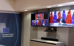 FILE - European Council President Charles Michel, right screen, waves to Chinese President Xi Jinping, left screen top, during an EU-China summit, in videoconference format, at the European Council in Brussels, June 22, 2020.