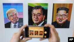 A visitor takes images, from left, of U.S. President Donald Trump, South Korean President Moon Jae-in and North Korean leader Kim Jong Un during an exhibition at an annex of the presidential Blue House in Seoul, South Korea, Jan. 3, 2019. 