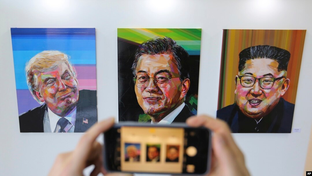 A visitor takes images, from left, of U.S. President Donald Trump, South Korean President Moon Jae-in and North Korean leader Kim Jong Un during an exhibition at an annex of the presidential Blue House in Seoul, South Korea, Jan. 3, 2019. 