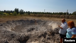 Local residents look at a crater created by Russian missile strike outside Kyiv, Ukraine, Aug. 18, 2024.