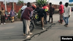 Des gens observent une fissure sur la route causée par les secousses qui ont suivi l'éruption du volcan Nyiragongo près de Goma, en République démocratique du Congo, le 26 mai 2021.