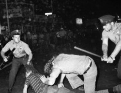 FILE - A New York Police officer grabs a youth by the hair as another officer clubs a young man during a confrontation in Greenwich Village after a Gay Power march in New York, Aug. 31, 1970.