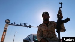 FILE - A member of Libyan forces loyal to eastern commander Khalifa Haftar holds a weapon as he sits on a car in front of the gate at Zueitina oil terminal in Zueitina, west of Benghazi, Libya, Sept. 14, 2016. 