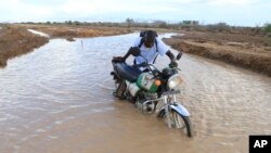 A motorcycle rider crosses a flooded section of the road in Hola, Kenya, on Nov. 7, 2023. Heavy rain and flooding killed 15 people in Kenya recently.