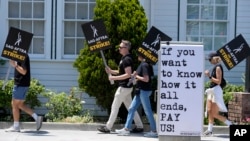 FILE - Picketers carry signs outside Amazon Studios in Culver City, Calif. on Monday, July 17, 2023. A tentative agreement between striking screenwriters and Hollywood studios offers some hope that the industry’s dual strikes may be over soon. (AP Photo/Chris Pizzello, File)