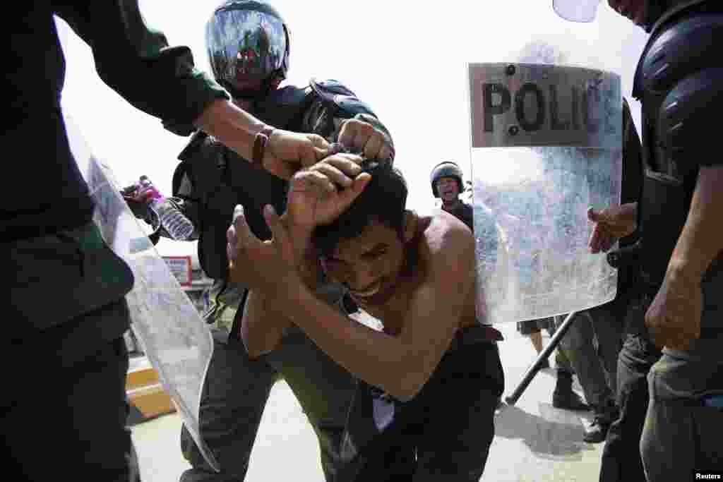 Policemen detain a man during clashes with garment workers in Phnom Penh, Nov. 12, 2013. 