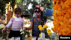 Los mexicanos adornan las tumbas de sus familiares desaparecidos con flores y velas en el Día de los Muertos.