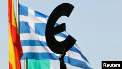 FILE - A Greek flag flies behind a statue to European unity outside the European Parliament in Brussels.