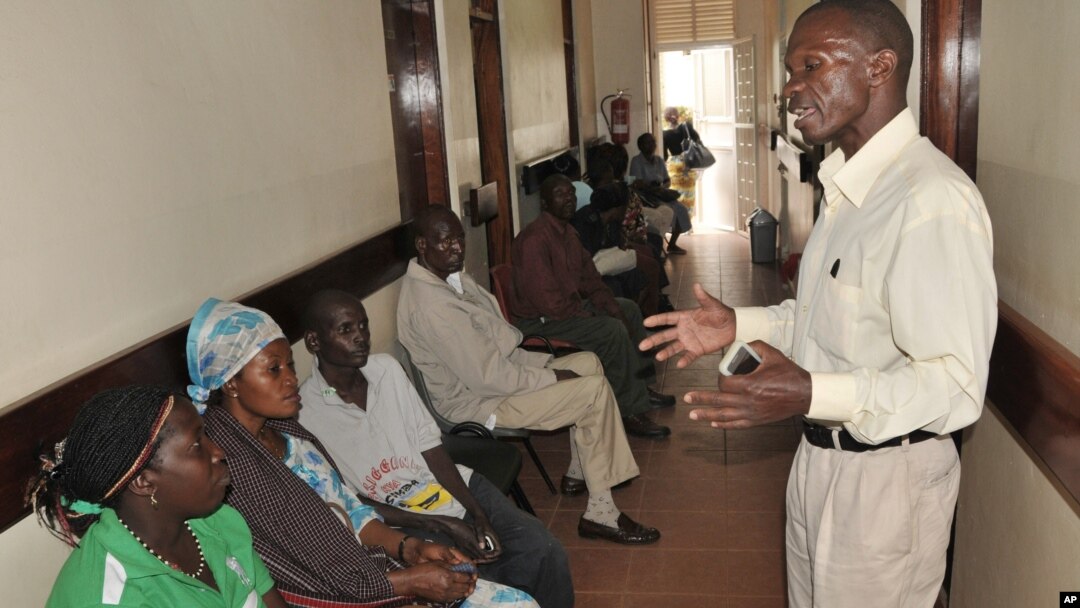 FILE - A health worker from The AIDS Support Organization (TASO) speaks with patients waiting for treatment in Kampala, Uganda.