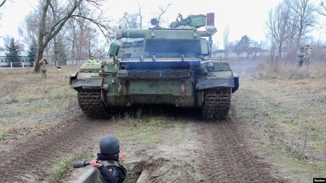 A reservist of the Ukrainian Territorial Defense Forces throws a dummy grenade towards an armored vehicle during military exercises at a training ground outside Kharkiv, Ukraine Dec. 11, 2021.