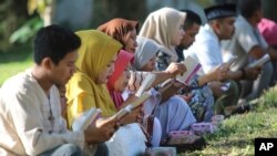 People pray at a mass grave site for the victims of the Indian Ocean tsunami, during the commemoration of the 15th anniversary of the disaster in Banda Aceh, Indonesia, Dec. 26, 2019.