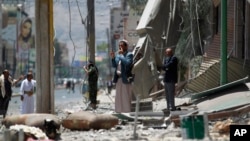 A man uses his cell phone to take pictures of houses destroyed by a Saudi-led airstrike in Sana'a, Yemen, June 8, 2015.