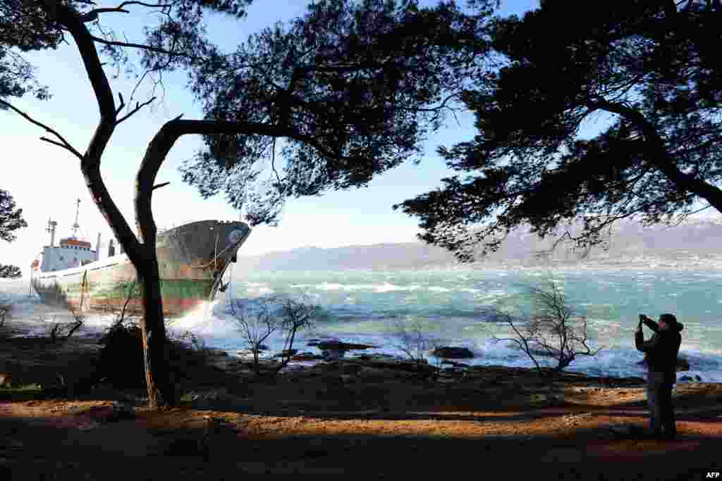 A man takes a picture of a ship that ran aground after a storm near the Adriatic city of Split, Croatia. Winds in the coastal city roared at a speed of 240 kilometers (150 miles) an hour, forcing the suspension of most ferry lines between the port and the islands.