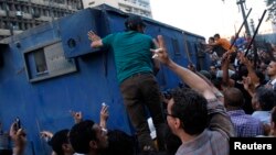 Supporters of the interim government installed by the army gather around a police van carrying Muslim Brotherhood supporters from the al-Fath mosque on Ramses Square in Cairo, Egypt, Aug. 17, 2013. 