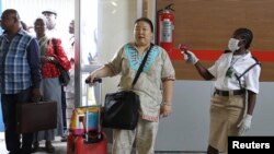 A female immigration officer uses an infra-red laser thermometer to examine a passenger at Nnamdi Azikiwe International Airport in Abuja, Nigeria, Aug. 11, 2014.