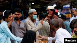 FILE - A man wearing a protective face mask gestures while shopping outside an electronics market, after Pakistan started easing lockdown restrictions, as the outbreak of the coronavirus disease continues, in Karachi, Pakistan June 4, 2020.