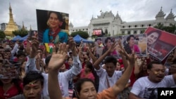 People hold the Myanmar national flag and placards as they attend a public gathering to listen to the live speech of Myanmar's State Counselor Aung San Suu Kyi in front of City Hall in Yangon on September 19, 2017. 