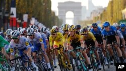 Slovenia's Tadej Pogacar, wearing the overall leader's yellow jersey, center, rides down Champs Elysees with the pack during the Tour de France on Sept. 20, 2020.