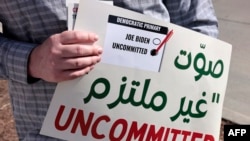 A volunteer holds a sign asking people to vote uncommitted, instead of for US President Joe Biden, outside of Maples School in Dearborn, Michigan, on Feb. 27, 2024.