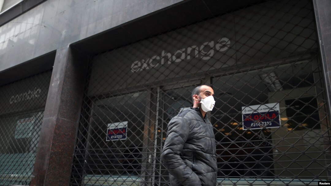 Un hombre usando una mascarilla pasa frente a un casa de cambio cerrada debido a la cuarentena, en el centro de Buenos Aires el 22 de mayo de 2020.