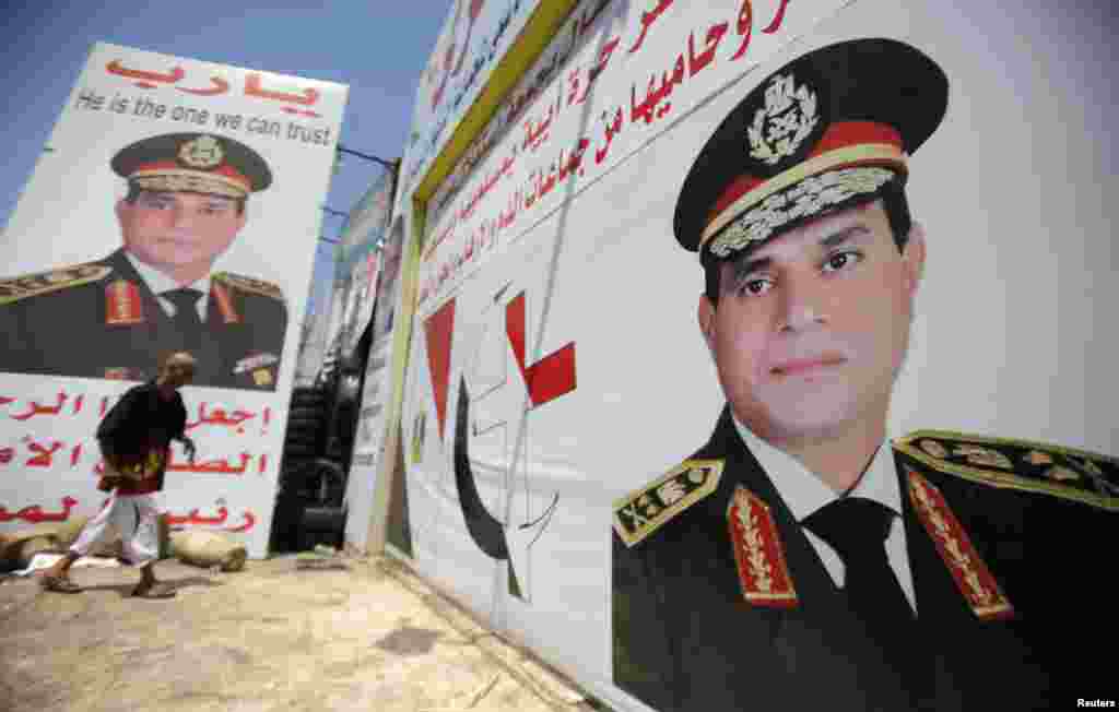 Salah Abdel Moneim, an anti-Morsi supporter of Egypt&#39;s army, walks in front of his shop, plastered with huge posters of Egypt&#39;s army chief General Abdel Fattah al-Sisi, Cairo, August 7, 2013. 