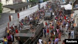 FILE - Army soldiers in an armored vehicle leave the City of God slum after the visit by U.S. President Barack Obama in Rio de Janeiro, March 20, 2011. 