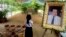 FILE - A girl stands by a portrait of Kem Ley, a Cambodian prominent political analyst, at his grave in Ang Takok, Cambodia, Nov. 20, 2016.