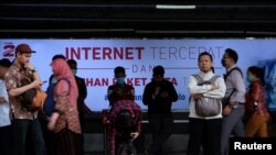 Para pengguna kereta api menunggu di depan iklan penyedia jasa layanan internet di Stasiun Sudirman, Jakarta, 9 Agustus 2016. (Foto: Reuters)