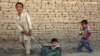 Anak-anak Afghanistan terlihat gembira bermain dengan mainan seadanya, tampak seorang anak laki-laki menarik adiknya yang duduk di sebuah keranjang di pinggiran Kabul.