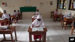 Para siswa sebuah SD di Jakarta mengenakan masker dan duduk dengan jarak aman dalam uji coba pembelajaran tatap muka, 4 Juni 2021. (AP/Tatan Syuflana)