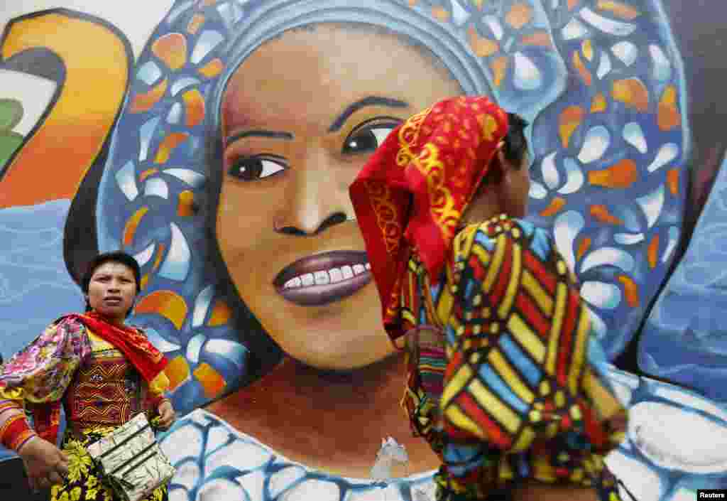 Guna Yala indigenous women walk past graffiti in the central town of Panama City, Panama, April 29, 2014.