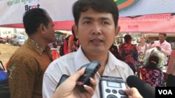 Ung Vuthy, local coordinator for CЕDAC, is seen being interviewed by reporters at the community market in Kompong Speu province. (Photo - Hul Reaksmey/VOA Khmer)