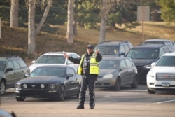 A Brookfield Police officer directs motorists out of the parking lot of Flatiron Crossing Mall as wildfires burned near the shopping center, near Broomfield, Colo., Dec. 30, 2021.