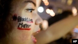 FILE - A woman with 'Black Lives Matter' written on her cheek demonstrates in Atlanta, Ga., against the deaths of unarmed black men at the hands of white police officers.