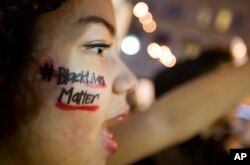 FILE - A woman with "Black Lives Matter" written across her cheek attends an Atlanta demonstration against the deaths of unarmed black men at the hands of white police officers.