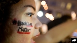 FILE - A woman with "Black Lives Matter" written across her cheek attends an ATlanta demonstration against the deaths of unarmed black men at the hands of white police officers.