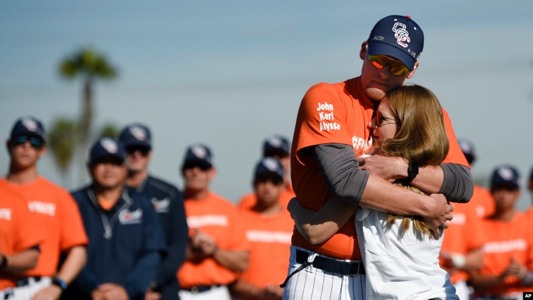 Associate coach Nate Johnson, left, embraces his wife Jonai during a ceremony held for John Altobelli, the late head coach of Orange Coast College baseball, who died in a helicopter crash alongside Kobe Bryant in Costa Mesa, Calif., Jan. 28, 2020.