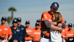 Associate coach Nate Johnson, left, embraces his wife Jonai during a ceremony held for John Altobelli, the late head coach of Orange Coast College baseball, who died in a helicopter crash alongside Kobe Bryant in Costa Mesa, Calif., Jan. 28, 2020.