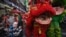 A laughing monk approaches a toddler as lion dancers perform on Yaowarat Road in Chinatown in Bangkok on Feb. 9, 2024, on the eve of the Lunar New Year.