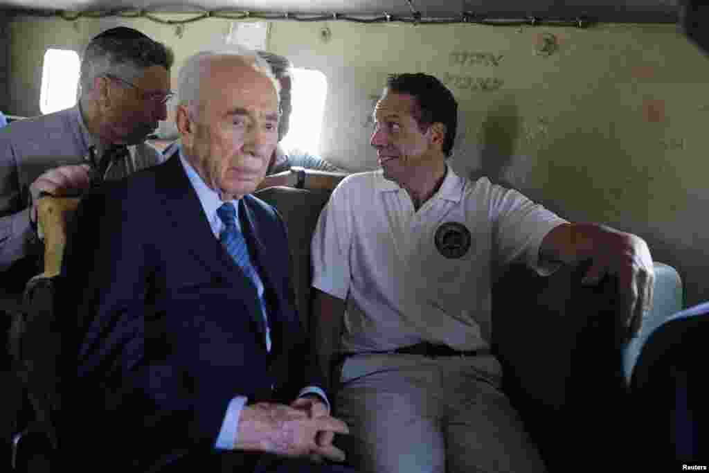 Former Israeli President Shimon Peres, second from left, and New York Governor Andrew Cuomo, right ride an armoured vehicle during a tour near the border with the Gaza Strip, Aug. 14, 2014.